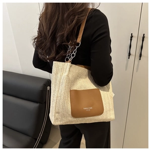 Detailansicht der braunen Kunstledertasche und Kettenträgerelemente der Stroh-Tote-Bag