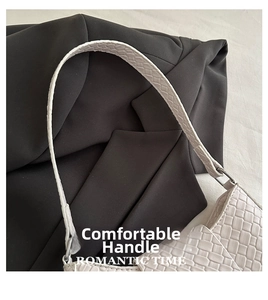 Detail of white woven texture underarm bag on dark suit with thin shoulder strap