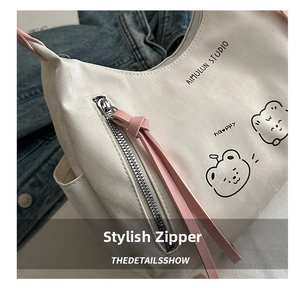 Detail shot of a white tote bag featuring a cute bear print and stylish pink zipper pulls