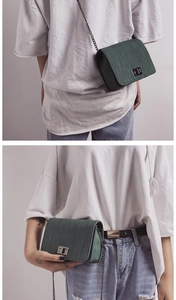 Detail view of a dark green square bag featuring vertical brushed texture and chain strap