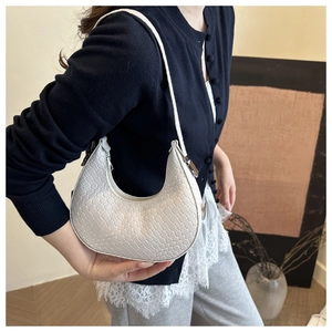 Close-up of a cream woven crescent shoulder bag featuring fine checkered texture design