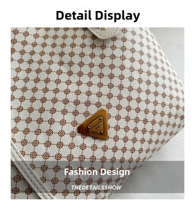 Détail du cuir à motif litchi et logo triangle en bronze sur le sac à bandoulière