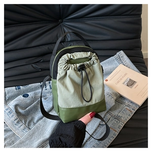 Detail of a green nylon mini drawstring crossbody bag with an adjustable shoulder strap