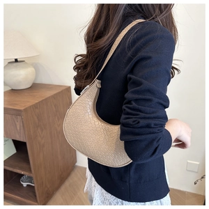 Detail of beige crescent underarm bag with plaid embossing shown on model shoulder