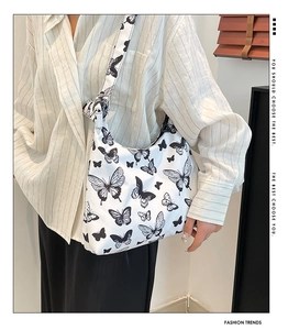 Dettaglio della borsa a tracolla bianca con farfalle nere e tracolla con nodo trendy