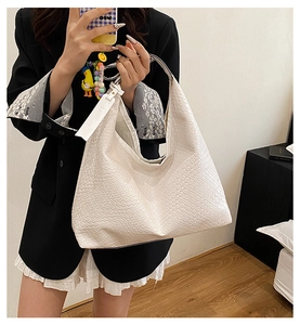Detail shot of the white woven texture and synthetic leather finish on a large tote bag