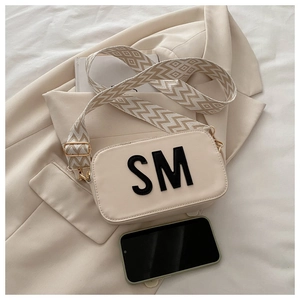 Détail du sac bandoulière beige en cuir avec logo SM et large bandoulière jacquard