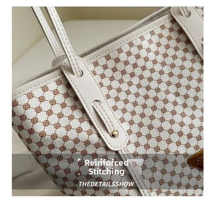 Détails des coutures renforcées et plaque dorée sur le sac cabas ivoire à fleurs