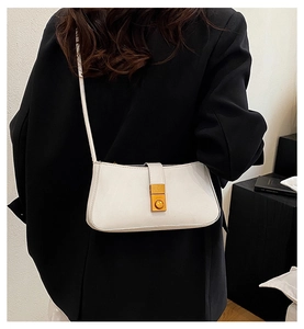 Detail of white leather underarm bag with gold metal buckle on a black blazer