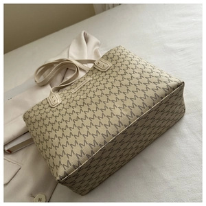 Detail of cream tote bag with grey M pattern and FASHION label on white fabric