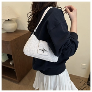 Close-up of white crocodile texture underarm bag with silver star buckle worn by model