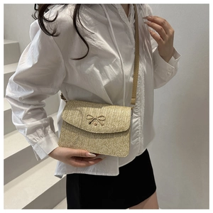 Detail of straw woven square bag with golden metal bow buckle and textured craftsmanship
