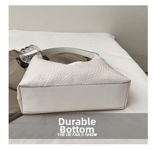 Close-up of the wear-resistant reinforced bottom of the white woven leather tote bag