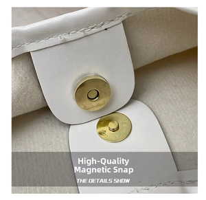 Detailed close-up of premium light gold magnetic clasp on a white leather tote bag