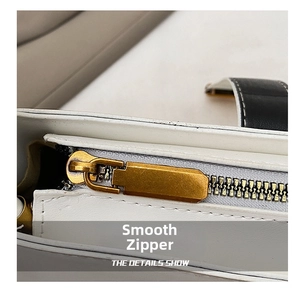 Detail of premium gold metal zipper and fine stitching on white leather bag