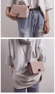 Detail of light pink mini square bag featuring textured leather and metal chain strap