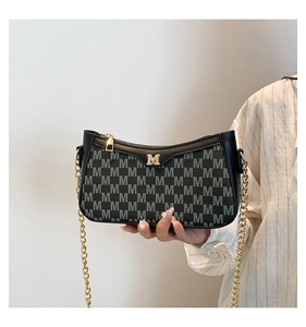 Detail of dark green monogram shoulder bag with gold M-logo and metal chain strap