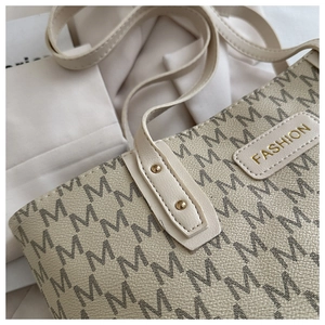 Detail of cream tote bag with letter print, gold fashion tag and premium stitching
