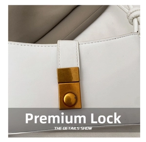 Detail of premium gold metal clasp on white leather minimalist baguette shoulder bag