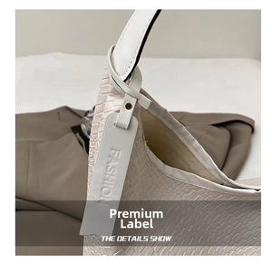 Detail of white crocodile texture leather tote bag featuring a Fashion brand tag