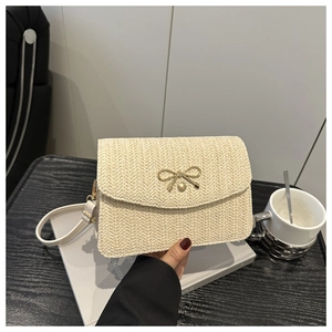 Dettaglio della borsa a tracolla in paglia beige con chiusura a fiocco dorata