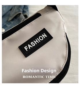 Detail of off-white canvas crossbody bag with black FASHION rubber patch and zipper