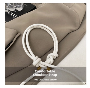 Detail shot of white leather knotted shoulder strap with fine stitching on a blazer