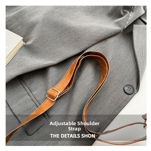 Close-up of adjustable brown leather shoulder strap with gold buckle on crossbody bag