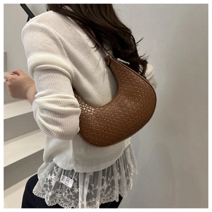 Close-up of brown textured woven crescent bag on shoulder for daily casual styling