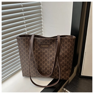 Close-up of a vintage brown tote bag with M-pattern print and gold FASHION plaque