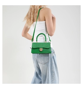 Detail view of emerald green glitter handbag with gold twist lock on model side profile
