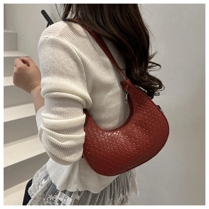 Detailed macro view of dark red woven texture on a minimalist crescent underarm bag