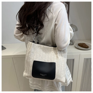 Detail of woven tote bag featuring a leather pocket and silver metal chain strap