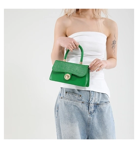 Detail of glittery green square bag with gold round turn-lock clasp and curved handle