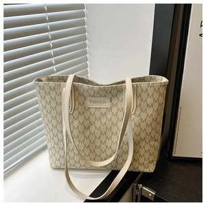 Detailed close-up of cream monogram tote bag with embossed fashion logo and textured leather