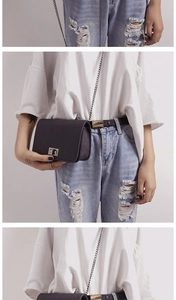 Detail view of the metal chain strap and rotating lock on a black crossbody bag