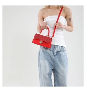 Detail of red glitter crossbody bag showing elegant gold circular twist lock closure