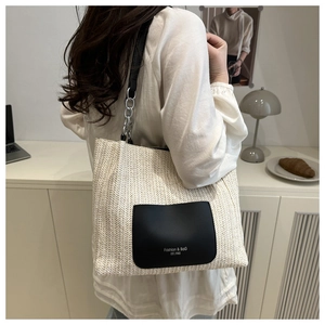 Detail der Strohtasche mit schwarzer Ledertasche und Metallkette an einem Modell