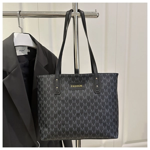 Detail of black tote bag with gray M letter pattern and golden Fashion logo label