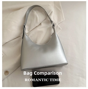 Detail view of a silver metallic hobo bag size comparison with a smartphone on fabric