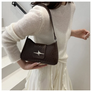 Detail of dark brown woven texture shoulder bag with silver star buckle on model