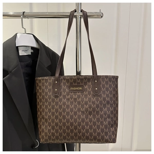 Macro detail of brown tote bag featuring luxury monogram pattern and golden metal logo