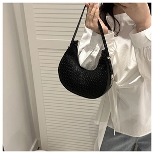 Detail of black woven crescent bag with silver metallic buckle on textured surface