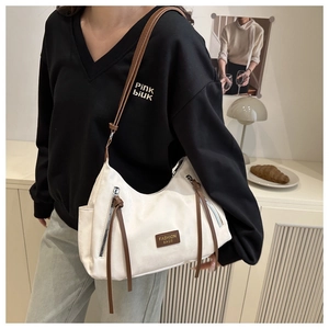 Detail of white hobo bag with brown tassels and leather fashion logo patch