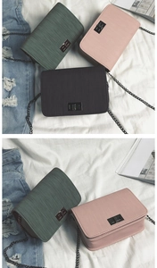 Close-up of minimalist textured crossbody bag with metal twist lock and chain strap detail