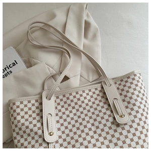 Gros plan d'un sac cabas beige à motifs géométriques marron sur un blazer beige
