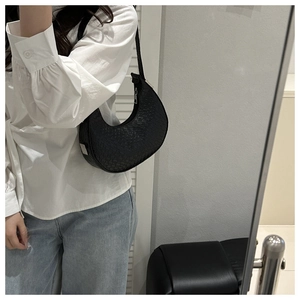 Mirror selfie showing the scale of a black crescent shoulder bag with woven texture