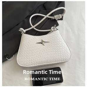 Detail view of white woven shoulder bag featuring silver star stud and rope handle