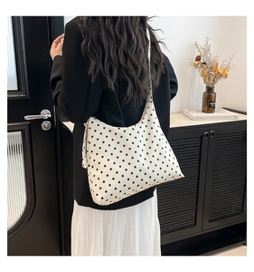 Vista posteriore di una modella con borsa a tracolla a mezzaluna a pois bianchi e neri
