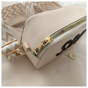 Détail de la fermeture éclair dorée et de la bandoulière en jacquard du sac beige